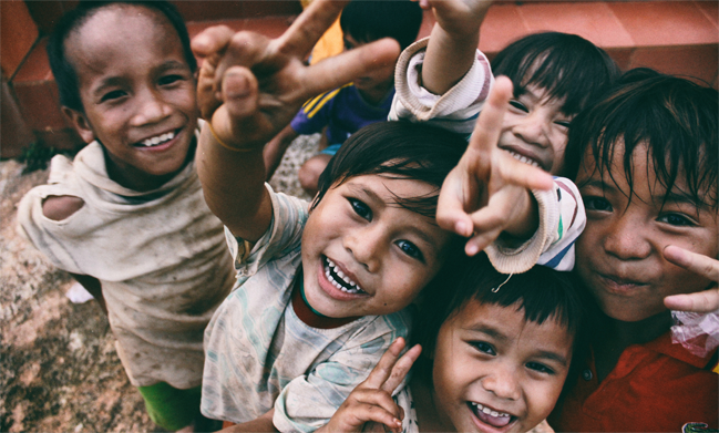 A group of smiling children showing the peace signs towards the camera