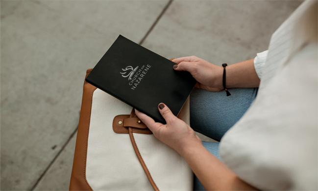 A lady holding a book with the church of the nazarene logo on it