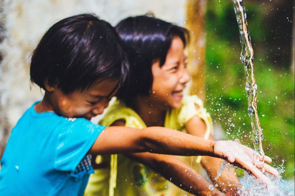 two kids playing with running water.